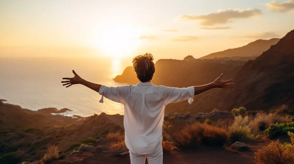 A man standing on a cliff overlooking the ocean