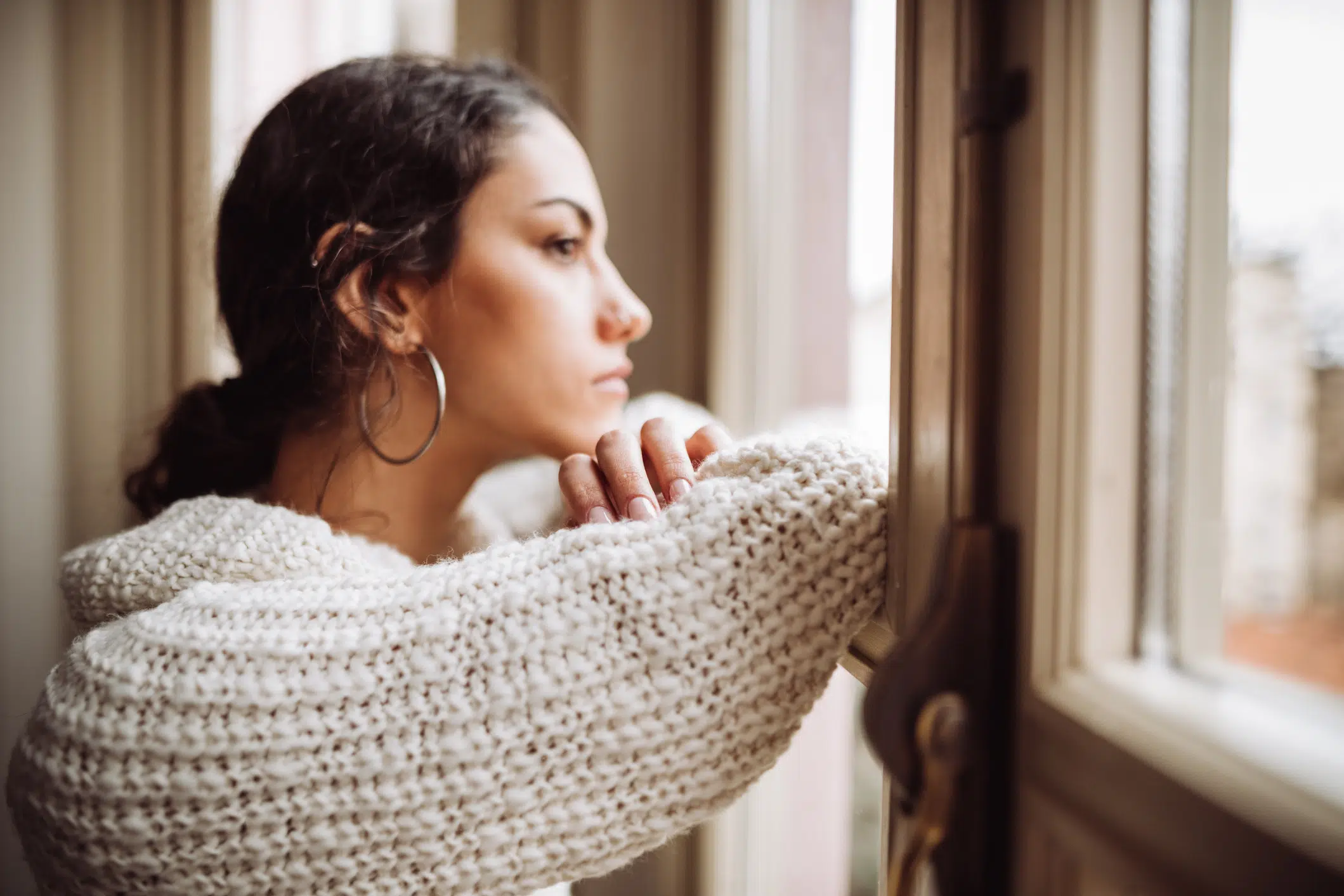 Woman stares out the window struggling with adjusting to postpandemic life