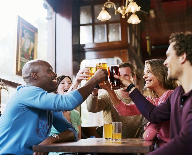 Group of friends toast beers at a pub