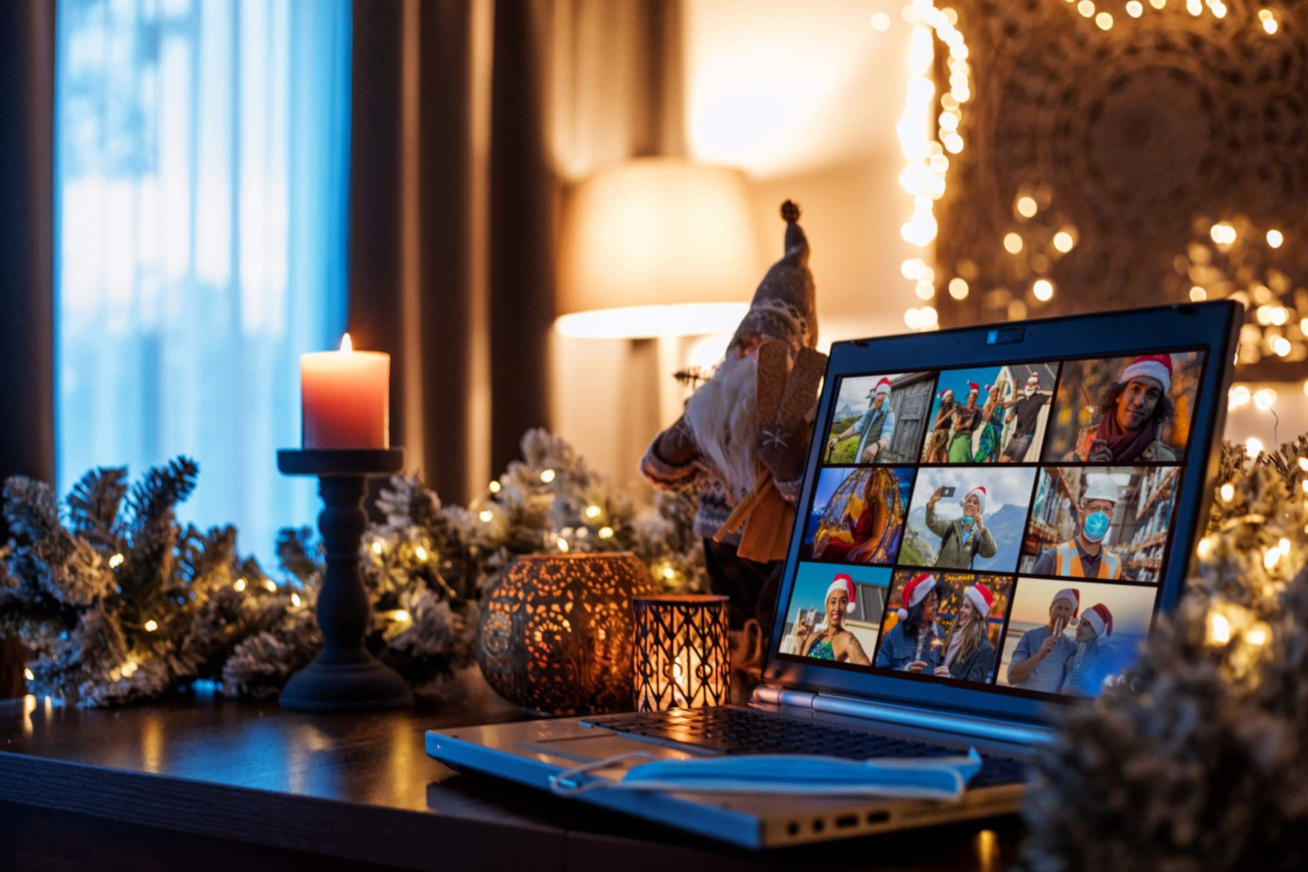 Laptop surrounded by holiday decor showing zoom screen of family members celebrating