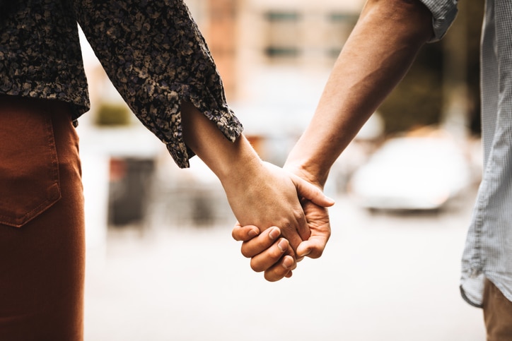 Couple holds hands while walking on date.