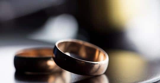 Wedding rings laying on table representing the end of a marriage.