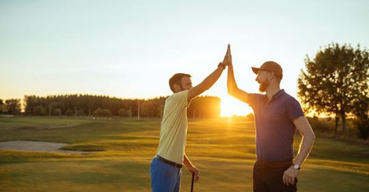 Men friends high five on the golf course