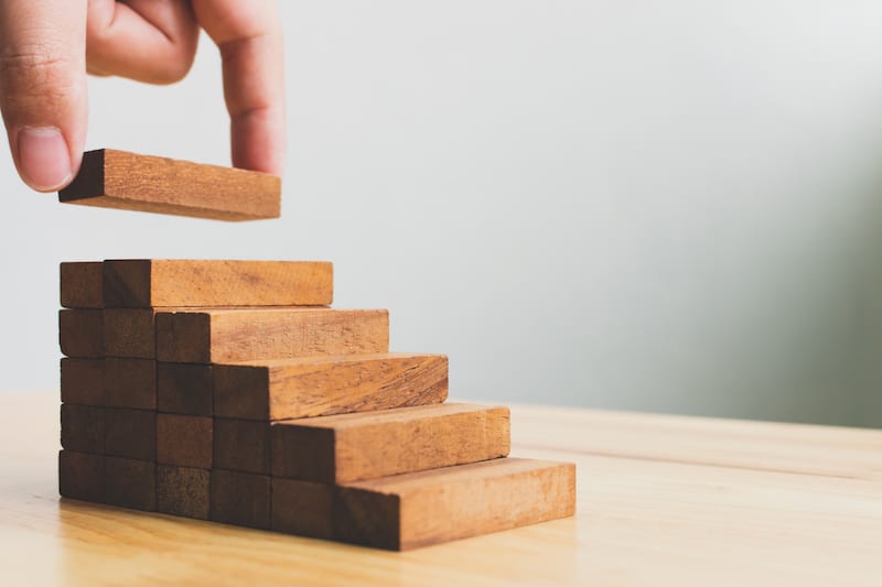 Hand arranging wood block stack representing self-development