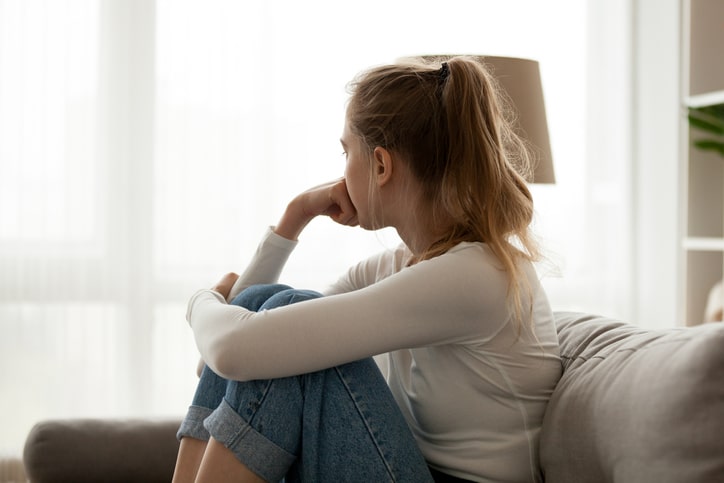 Woman sits on couch worrying about the future