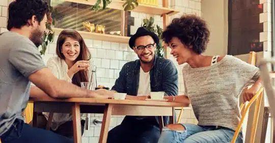 Man chats with friends in restaurant as selfcare