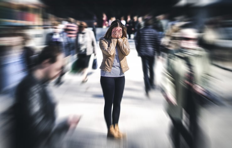 Woman covers face while having a panic attack in public.