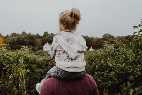 Young girl rides on adoptive father's shoulders.