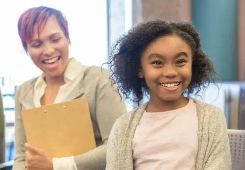 Young girl talks with teacher in school