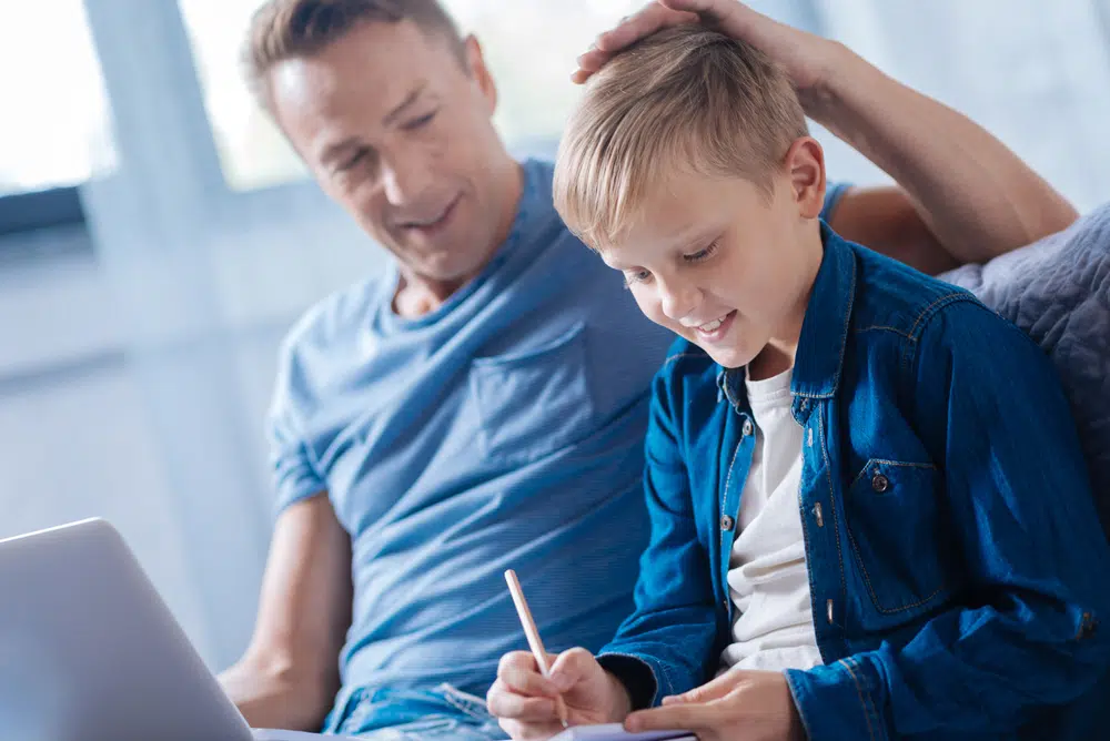 Proud father patting son on the head while he studying