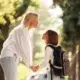 Parent holding hands with a school-age child wearing a backpack during the fall school season