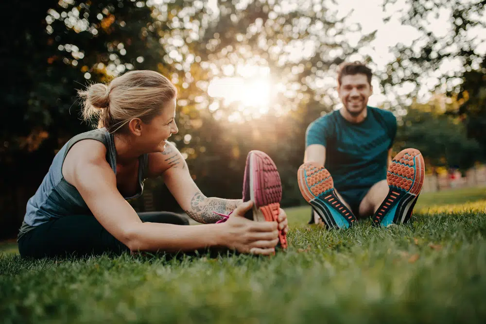 Couple stretching after exercising outdoors for mental health