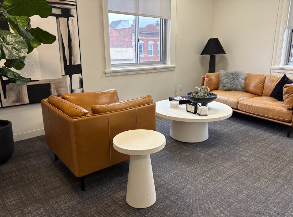 Consultation room with a tan leather sofa and armchair at the Lukin Center Englewood office