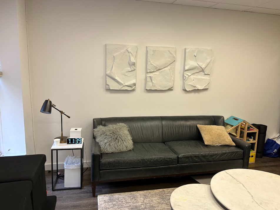 Therapy room with a leather sofa and textured wall art at the Lukin Center Hoboken office