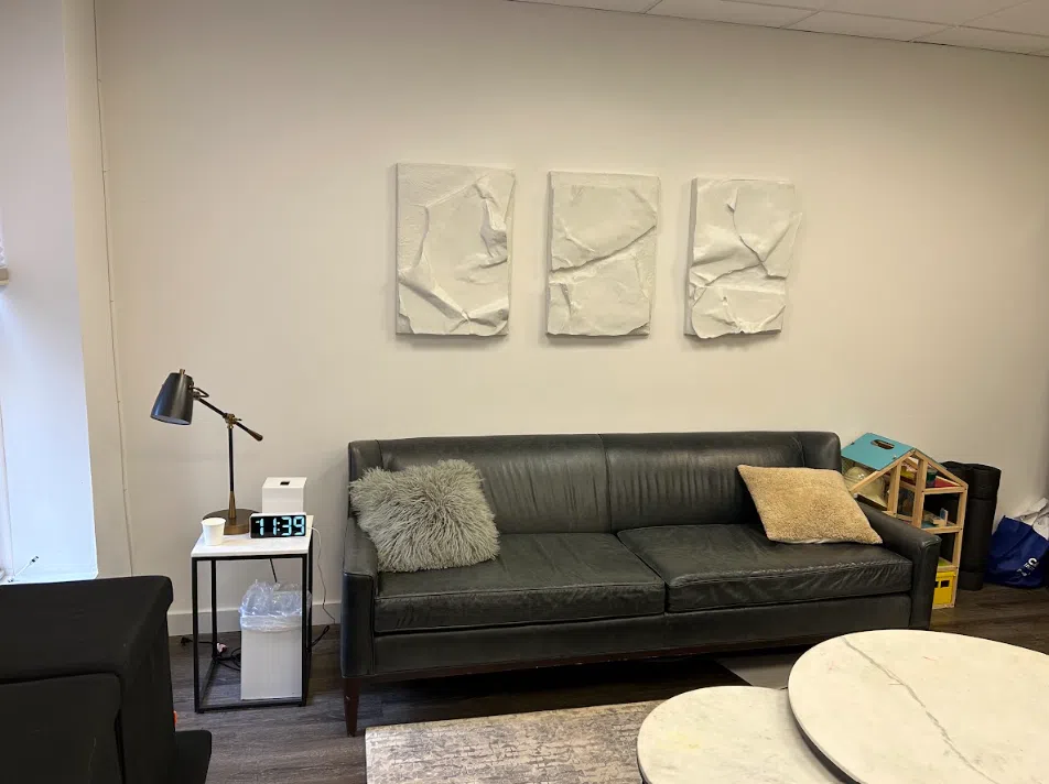 Therapy room with a leather sofa and textured wall art at the Lukin Center Hoboken office