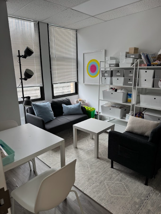 Bright therapy office with a sofa and shelving at the Lukin Center Jersey City office