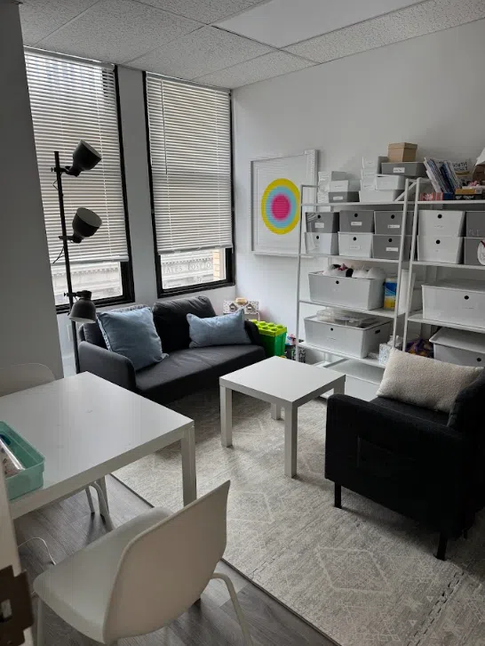 Bright therapy office with a sofa and shelving at the Lukin Center Jersey City office