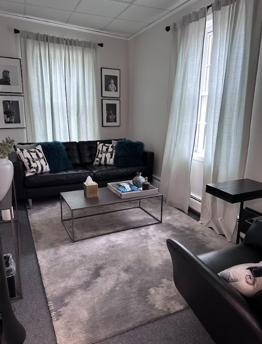 Therapy office with a black leather sofa and bright windows at the Lukin Center Montclair office