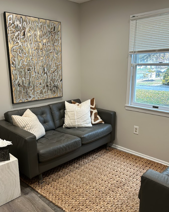 Therapy room with a leather loveseat and large abstract art at the Lukin Center Westfield office