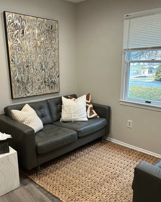 Therapy room with a leather loveseat and large abstract art at the Lukin Center Westfield office