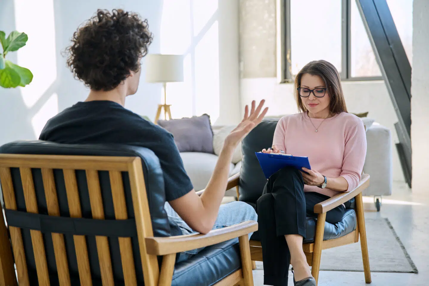 A therapist taking notes while speaking with a patient.