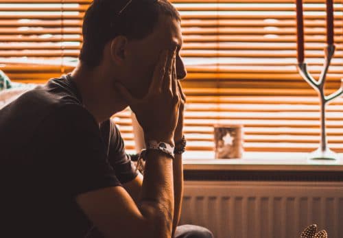 Man sits on couch in the dark dealing with stress and trauma issues.