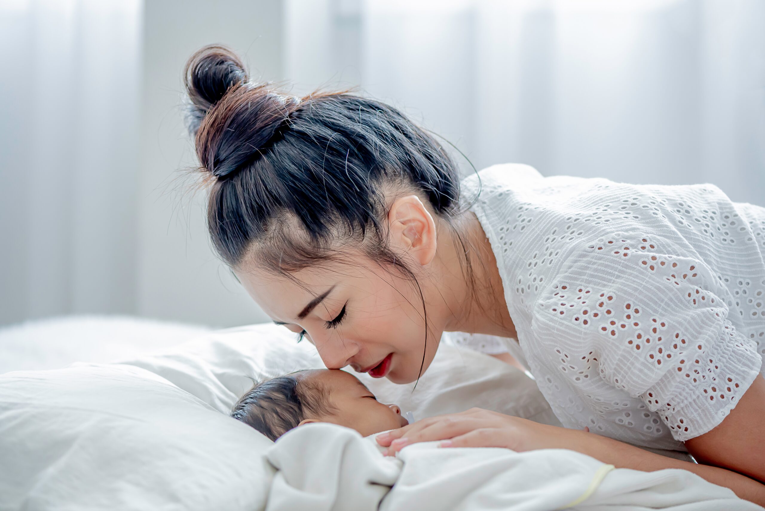 A mother laying in bed with her baby for the topic postpartum mental health.