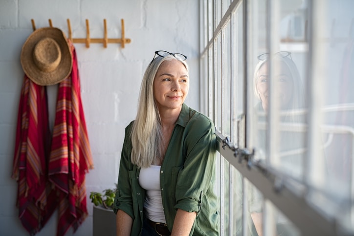 Woman stares out window considering the uncertainty of the times we live in.