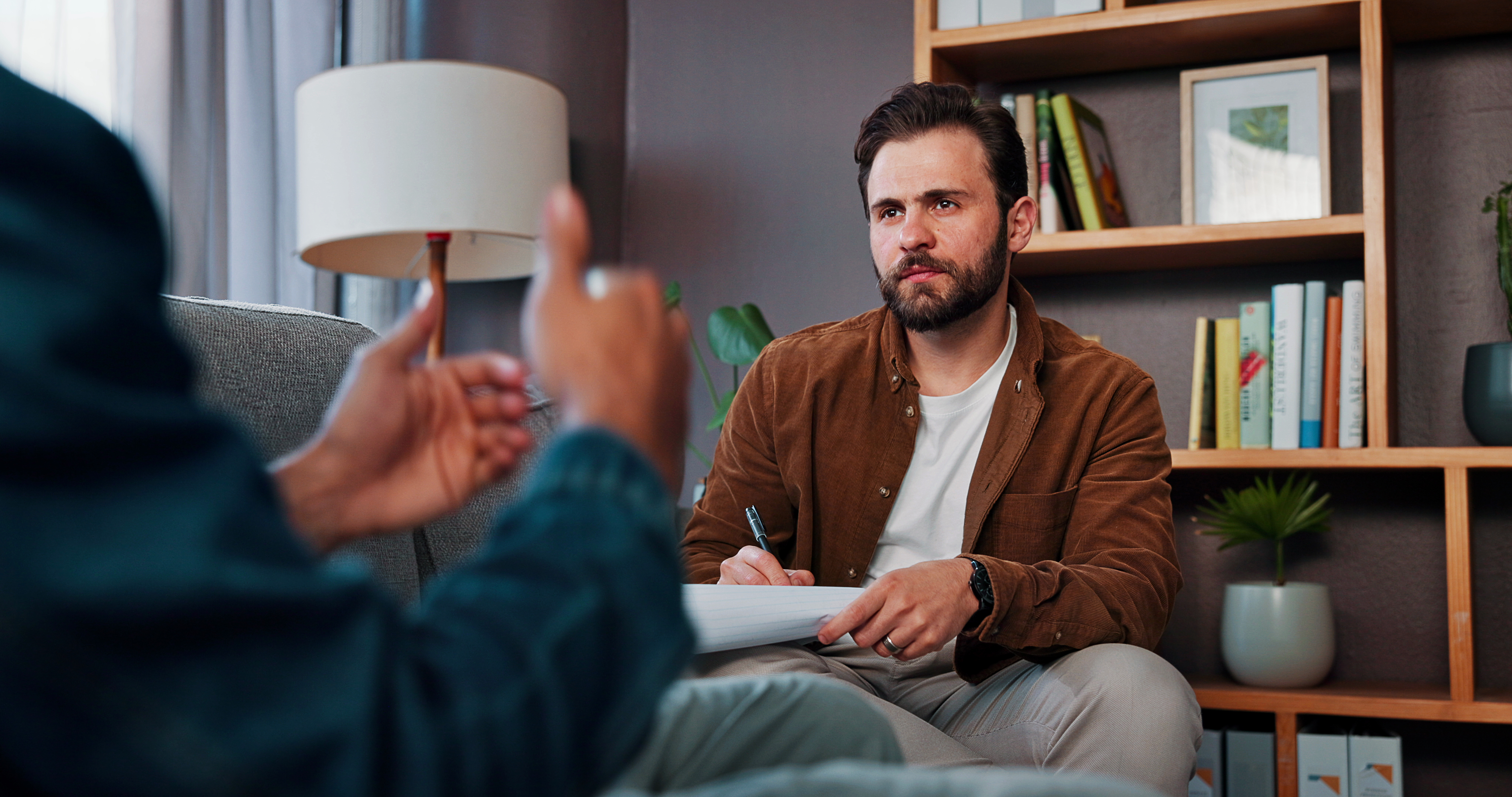 A therapist holding a notepad while speaking with a patient for the topic does insurance cover therapy.