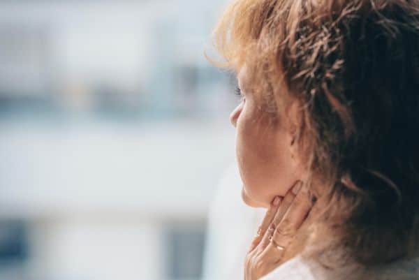 Woman with PTSD looks out window.