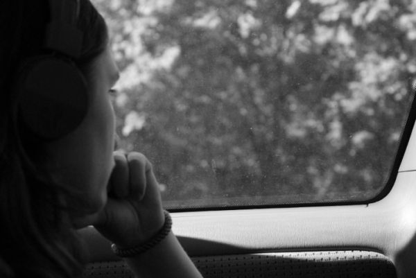 Troubled woman struggling with self injury stares out car window