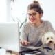 Woman works on laptop with dog on lap for mental health