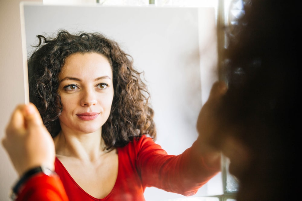Woman having an identity crisis looks at herself in a mirror.