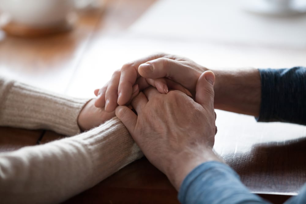 Adults holding hands and sharing empathy.