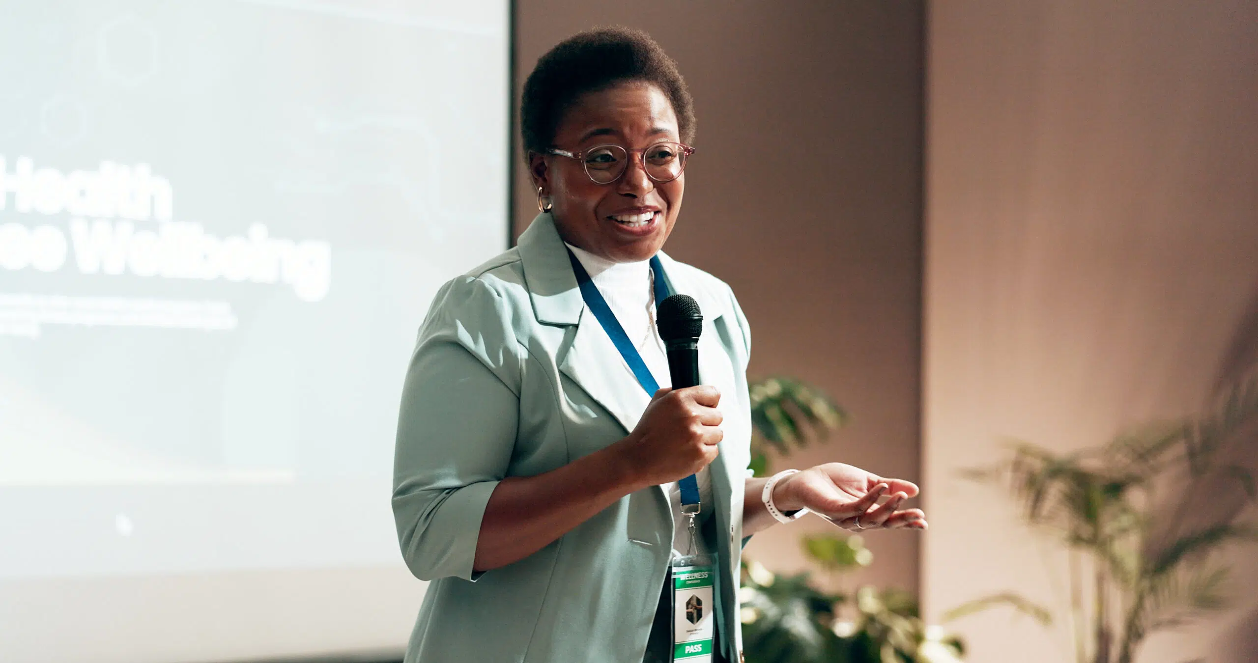A woman holding a microphone and speaking at a world mental health day event.