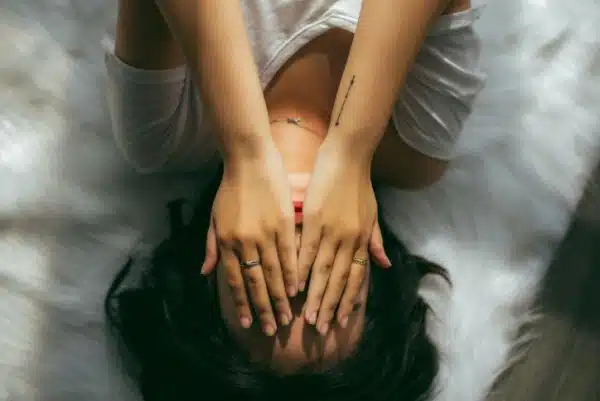 Woman covers face as she copes with sexism, motherhood, infertility, worklife balance or gender inequality issues.